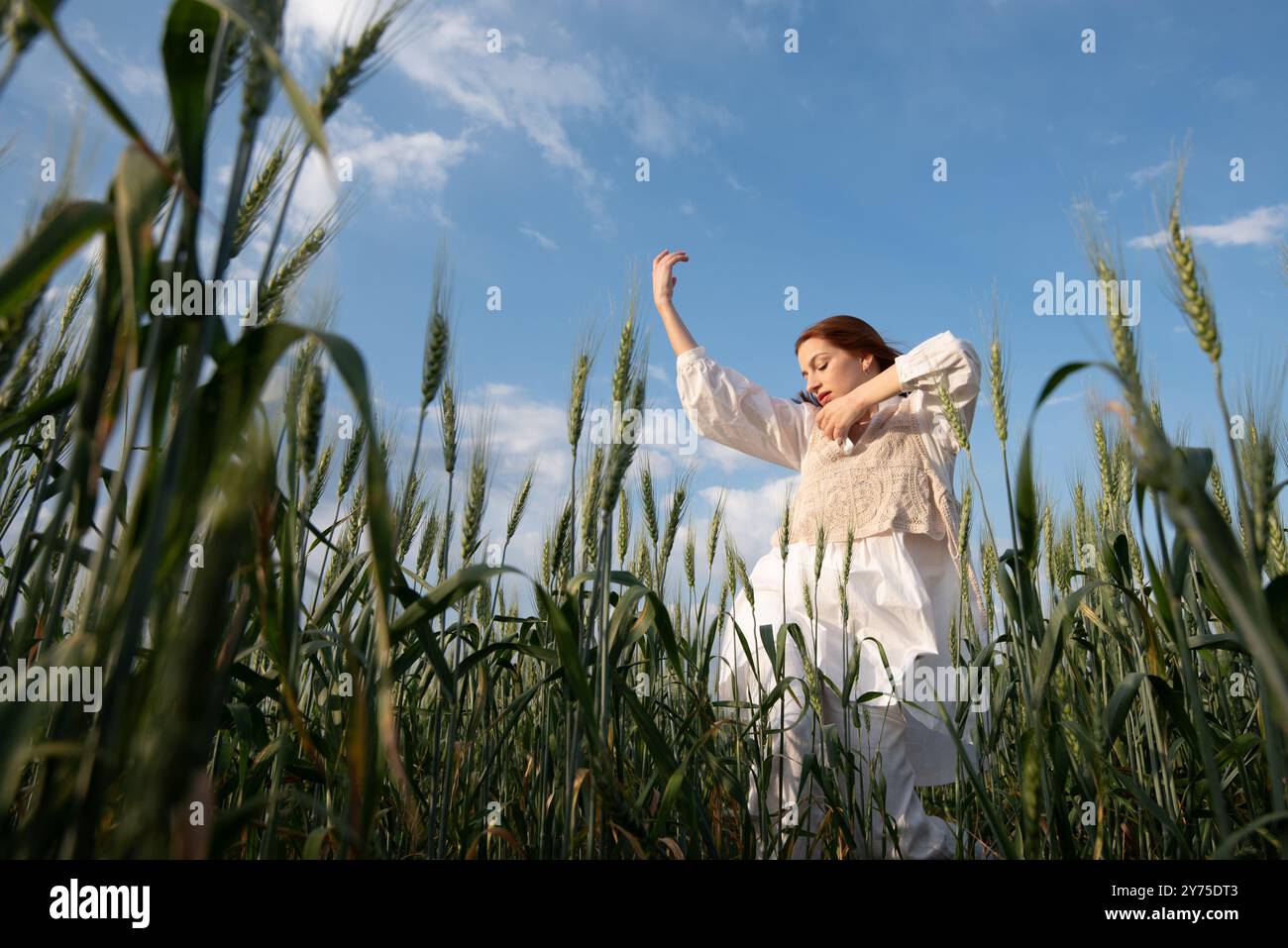 Eine junge Frau in weiß tanzt und berührt Weizen auf einem Feld A Stockfoto