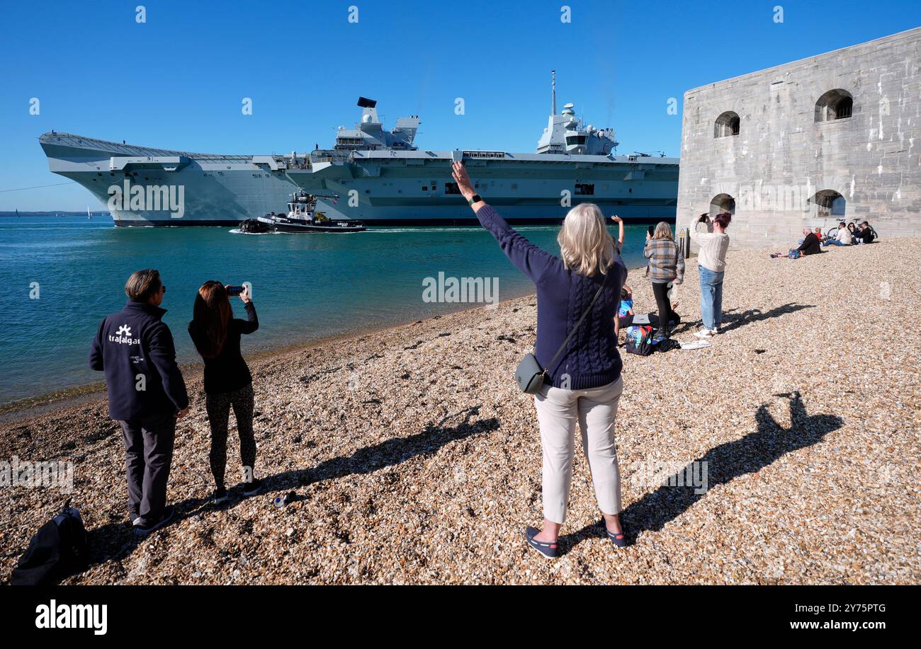 Die Leute schauen vom Strand von Hotwalls aus, während der Flugzeugträger der Royal Navy HMS Prince of Wales vom Hafen von Portsmouth aus die Segel setzt, bevor er die UK Carrier Strike Group bei einer großen Übung in der Nordsee anführt. Die 65.000-Tonnen-Fluggesellschaft wird zu einem kritischen Trainingsprogramm im Herbst starten - einschließlich der großen Übung Strike Warrior -, das ein wichtiger Schritt für das Schiff, ihre Fluggruppe und Begleitpersonen ist, bevor es im nächsten Jahr weltweit eingesetzt werden kann. Bilddatum: Samstag, 28. September 2024. Stockfoto