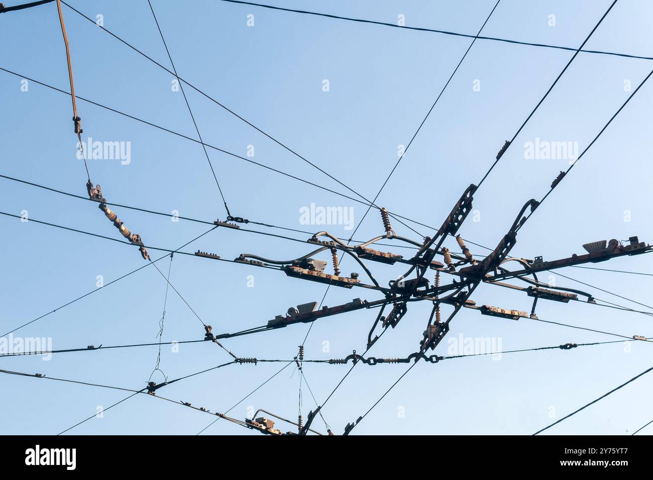 Industrieller urbaner Hintergrund, verflochtene Kabel über der Straße an der Kreuzung der Oberleitungsbuskontaktdrähte Stockfoto