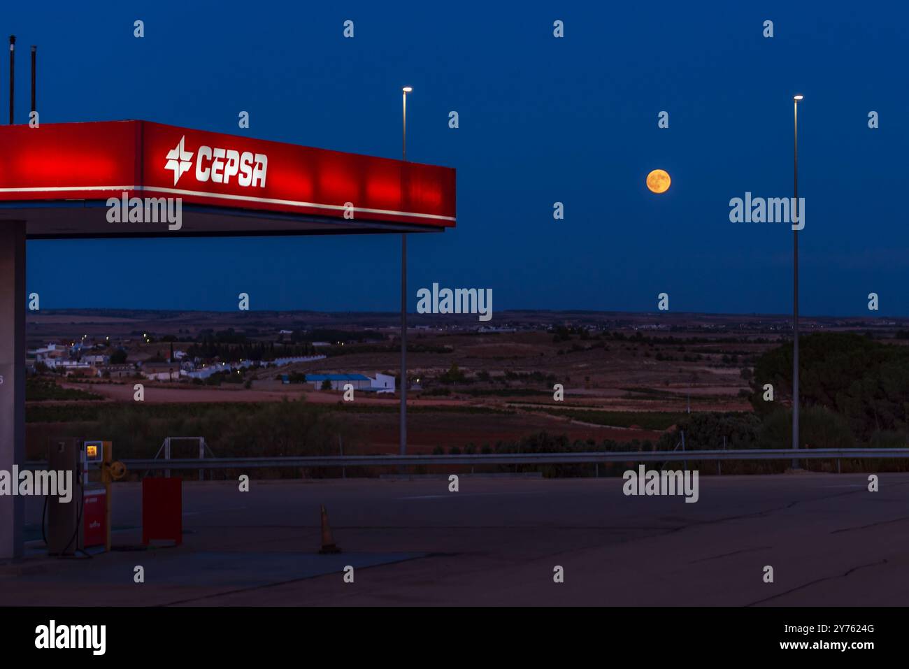 Baldachin einer Cepsa-Tankstelle mit Vollmond im Hintergrund während der blauen Morgenstunde. Stockfoto