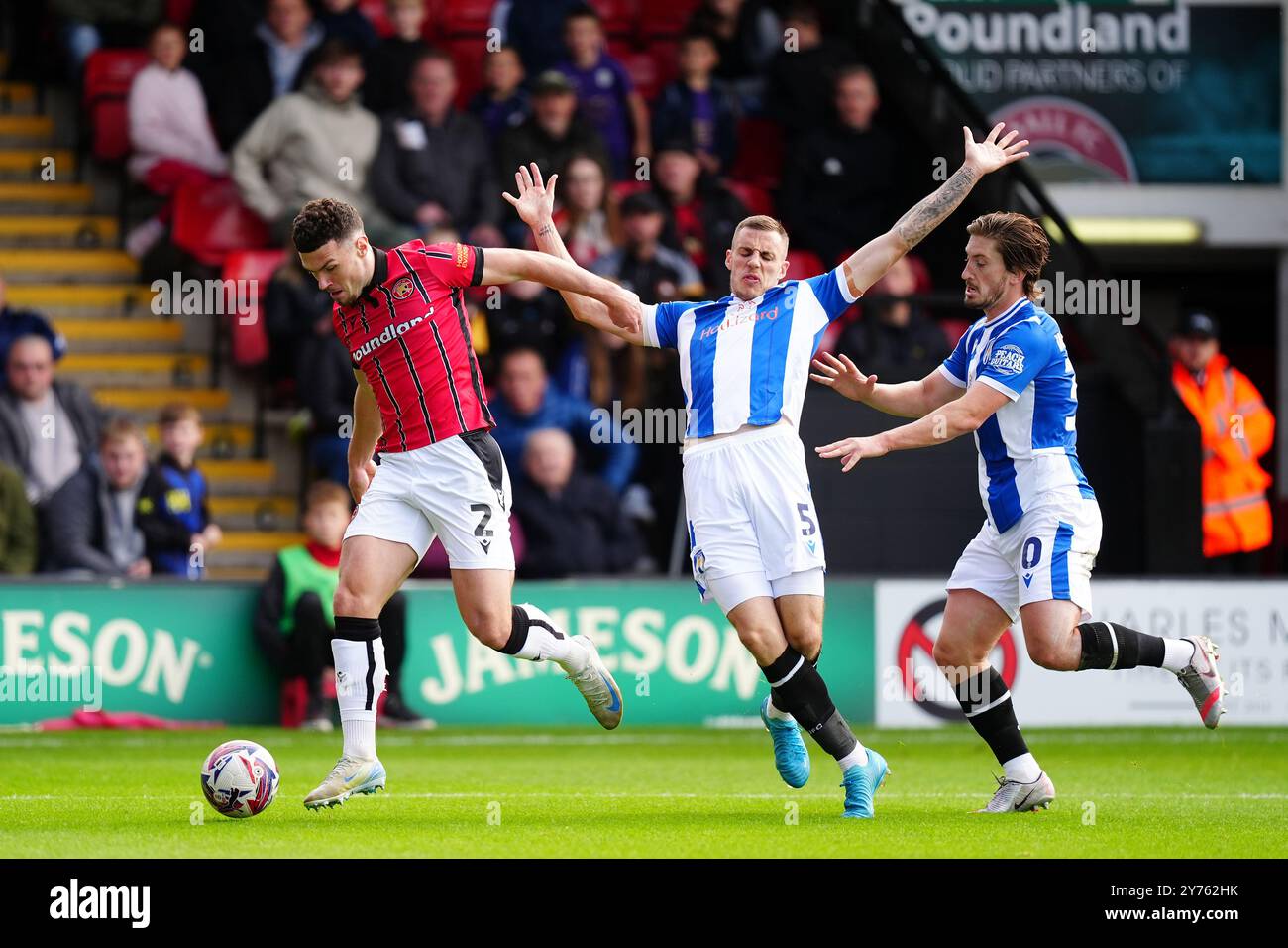 Walsalls Connor Barrett (links) und Ben Goodliffe (Mitte) von Colchester United kämpfen um den Ball während des Spiels der Sky Bet League Two im Poundland Bescot Stadium in Walsall. Bilddatum: Samstag, 28. September 2024. Stockfoto