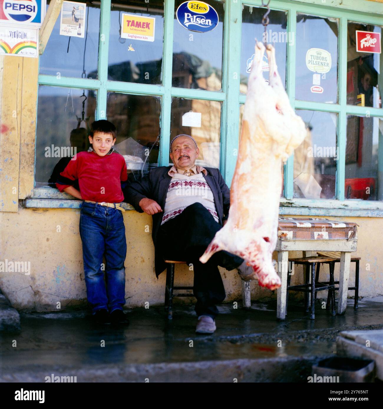 Ein Junge, ein Mann und ein geschlachtetes Tier vor einer Kneipe in einem Ort im Zigana-Pass (Zigana Gecidi) in der Provinz Trabzon oder Gümüshane (Gümüşhane) in Nordostanatolien, Türkei um 1988. Stockfoto