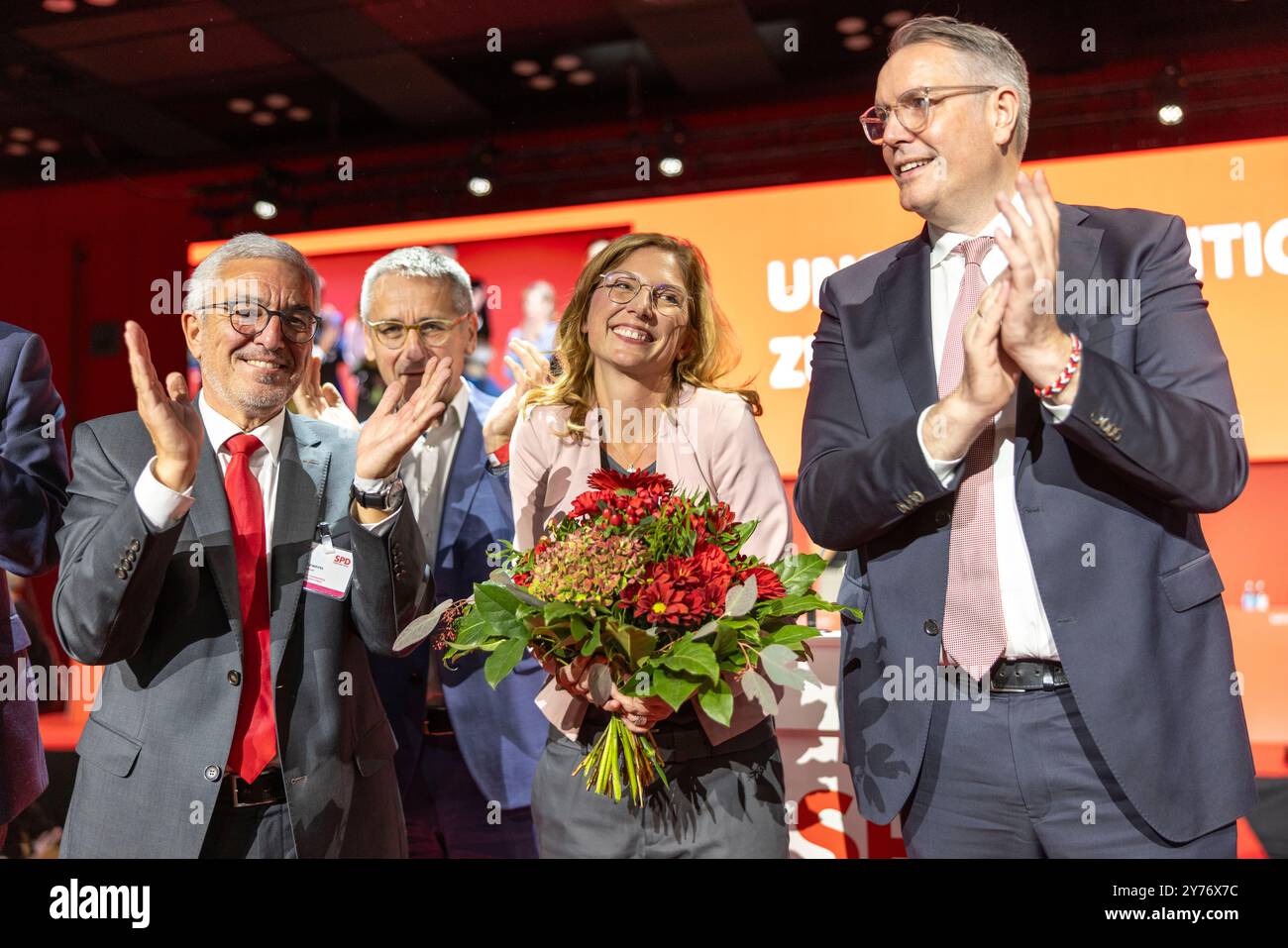 Mainz, Deutschland. September 2024. Der scheidende Rheinland-pfälzische SPD-Chef Roger Lewentz (l) und Alexander Schweitzer (SPD, r), Ministerpräsident Rheinland-Pfalz, klatschen bei der außerordentlichen Parteikonferenz der SPD Rheinland-Pfalz neben der neu gewählten Parteivorsitzenden Sabine Bätzing-Lichtenthäler. Hinter ihr steht ihr Mann Marco Lichtenthäler. Auch die Rheinland-pfälzische SPD hat auf der Parteikonferenz ihren Fraktionsvorsitzenden mit großer Mehrheit zum Parteivorsitzenden gewählt. Quelle: Helmut Fricke/dpa/Alamy Live News Stockfoto
