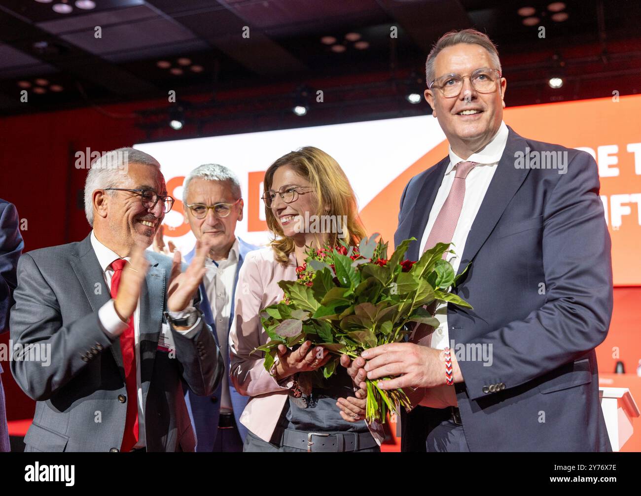 Mainz, Deutschland. September 2024. Der scheidende Rheinland-pfälzische SPD-Chef Roger Lewentz (l) und Alexander Schweitzer (SPD, r), Ministerpräsident Rheinland-Pfalz, klatschen bei der außerordentlichen Parteikonferenz der SPD Rheinland-Pfalz neben der neu gewählten Parteivorsitzenden Sabine Bätzing-Lichtenthäler. Hinter ihr steht ihr Mann Marco Lichtenthäler. Auch die Rheinland-pfälzische SPD hat auf der Parteikonferenz ihren Fraktionsvorsitzenden mit großer Mehrheit zum Parteivorsitzenden gewählt. Quelle: Helmut Fricke/dpa/Alamy Live News Stockfoto