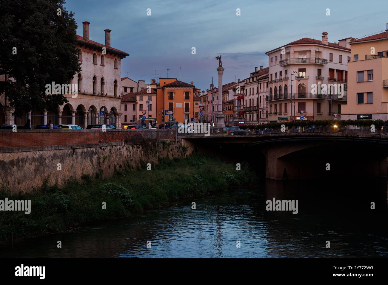 Vicenza, Italien - 13. September 2024: Ein Blick bei Sonnenuntergang auf einen ruhigen Fluss in Vicenza, mit dem berühmten Durchbruch des Porta Pia Monuments, Säule ri Stockfoto