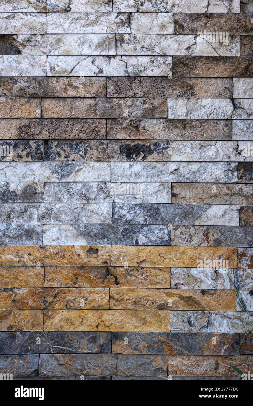 Eine Wand aus braunen und weißen Steinen. Die Mauer ist alt und hat ein verwittertes Aussehen. Stockfoto