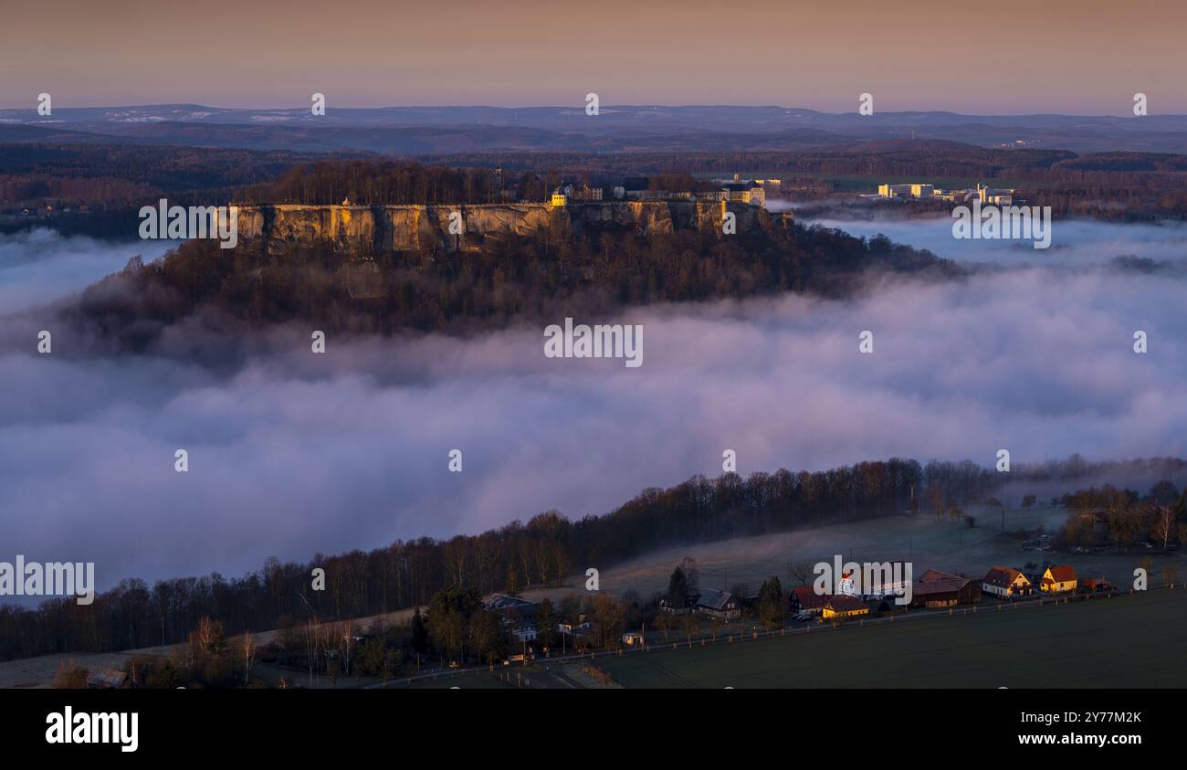 Hoch oben über dem Fluss Elbthront die Festung Königstein. Jahrhunderte als uneinnehmbar geltend, erscheint die sagenumwobene Burg im dichten Nebel. Stockfoto