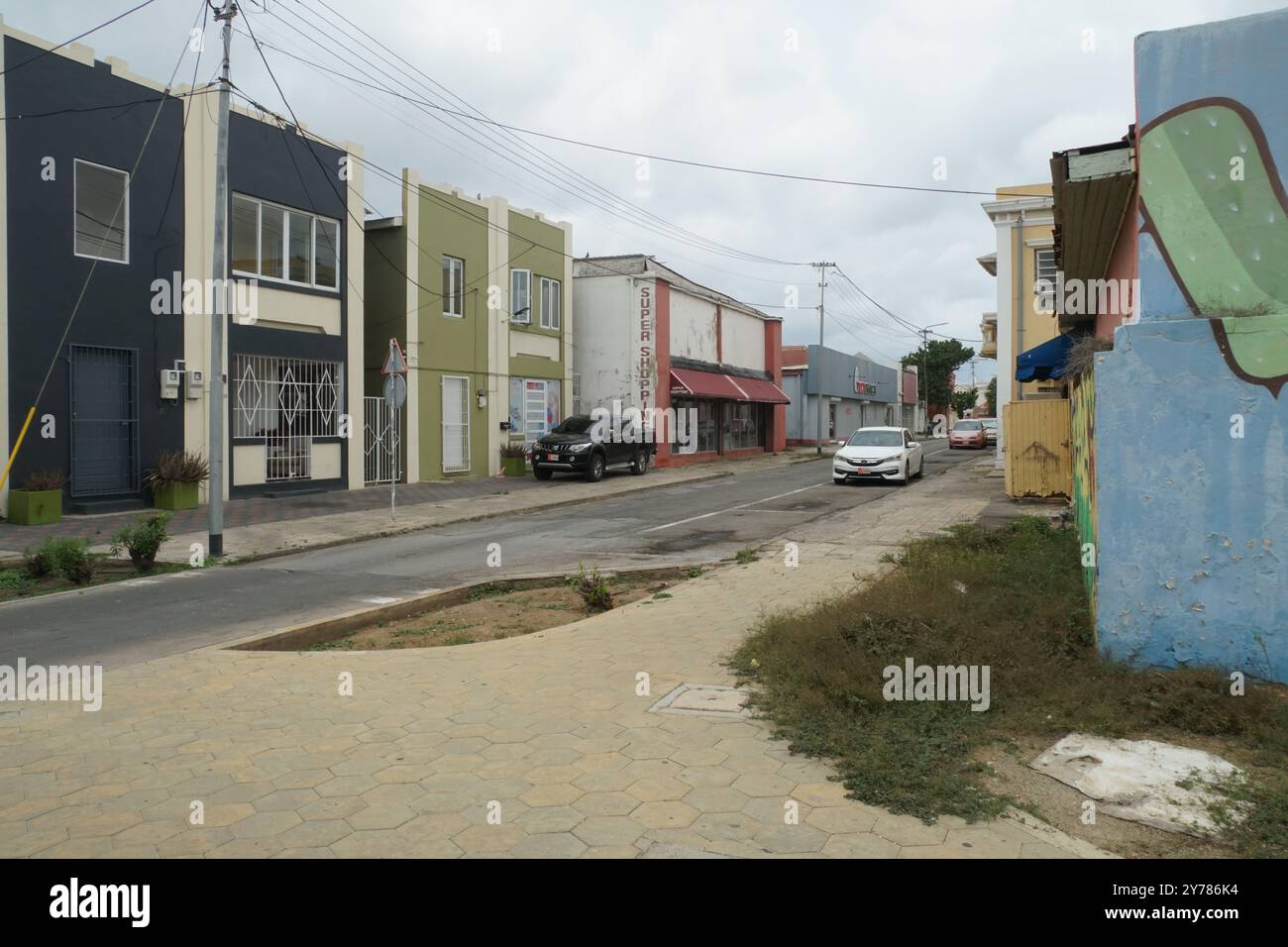 Vorort in der Nähe des Stadtzentrums mit farbenfrohen Gebäuden im Kolonialstil in einer engen Straße mit Palmen und einigen Autos in Oranjestad auf Aruba. Stockfoto