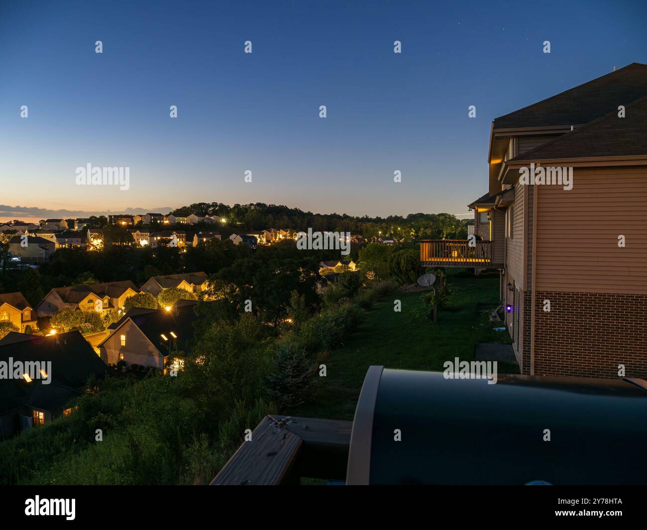 Ein ruhiger Abend in einem amerikanischen Viertel, wo warme Lichter von Vorstadtfenstern eine gemütliche, einladende Atmosphäre schaffen. Stockfoto