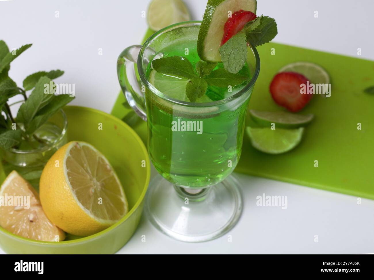 Grüne Limonade im Glas. Dekoriert mit Limette und Erdbeeren. Mit Minzzweigen. In der Nähe von Zitrone und Minze. Stockfoto