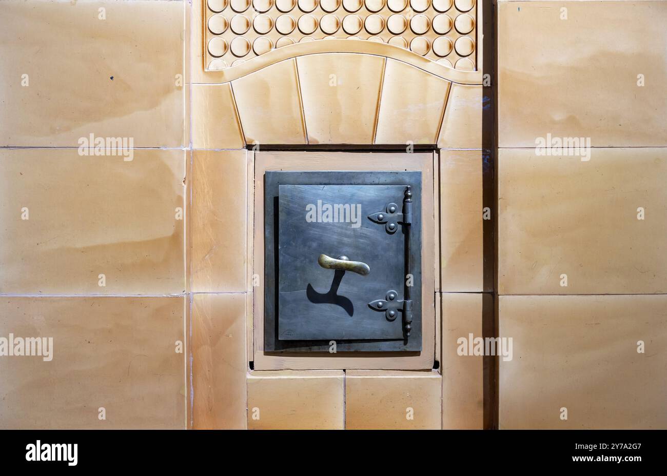 Die Tür eines alten Ofens, in den Feuerholz gelegt wurde. Stockfoto