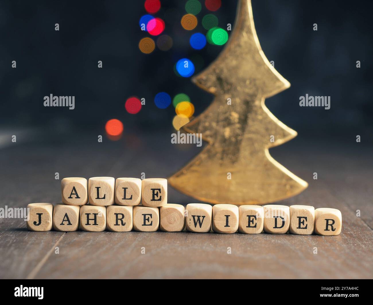 Holzwürfel mit deutscher Inschrift jedes Jahr wieder, weihnachtskonzepthintergrund mit verschwommenen Weihnachtslichtern Stockfoto