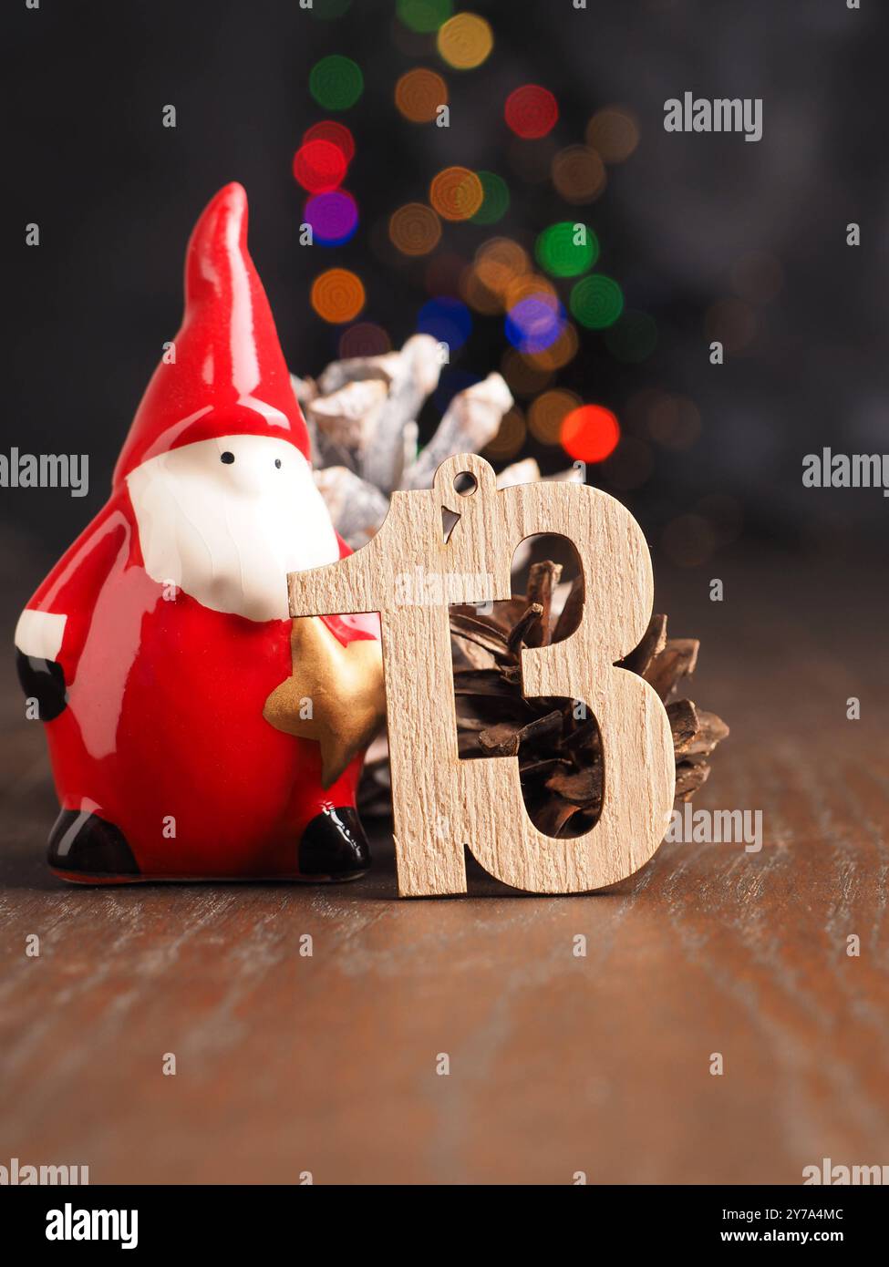 13. Dezember hölzerne Nummer 13 mit einem Kiefernkegel auf verschwommenem Weihnachtslicht Stockfoto