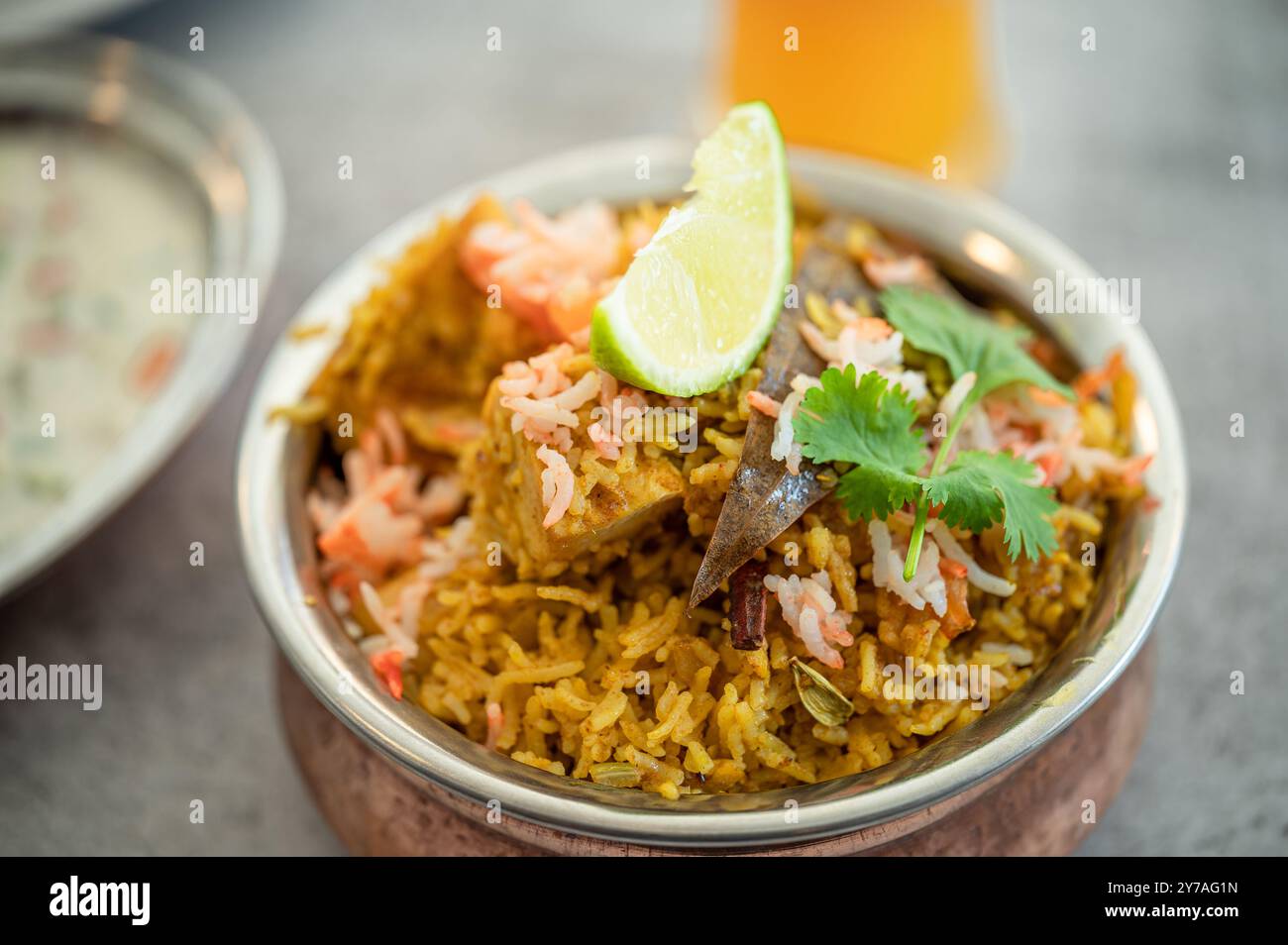 Würziger indischer Biryani-Pulao in goldener Schüssel mit indischem Basmati-Reisgericht mit Hühnerfleisch-Curry Ramadan Kareem, Eid. Servierschale aus Messing mit weißem Rücken Stockfoto