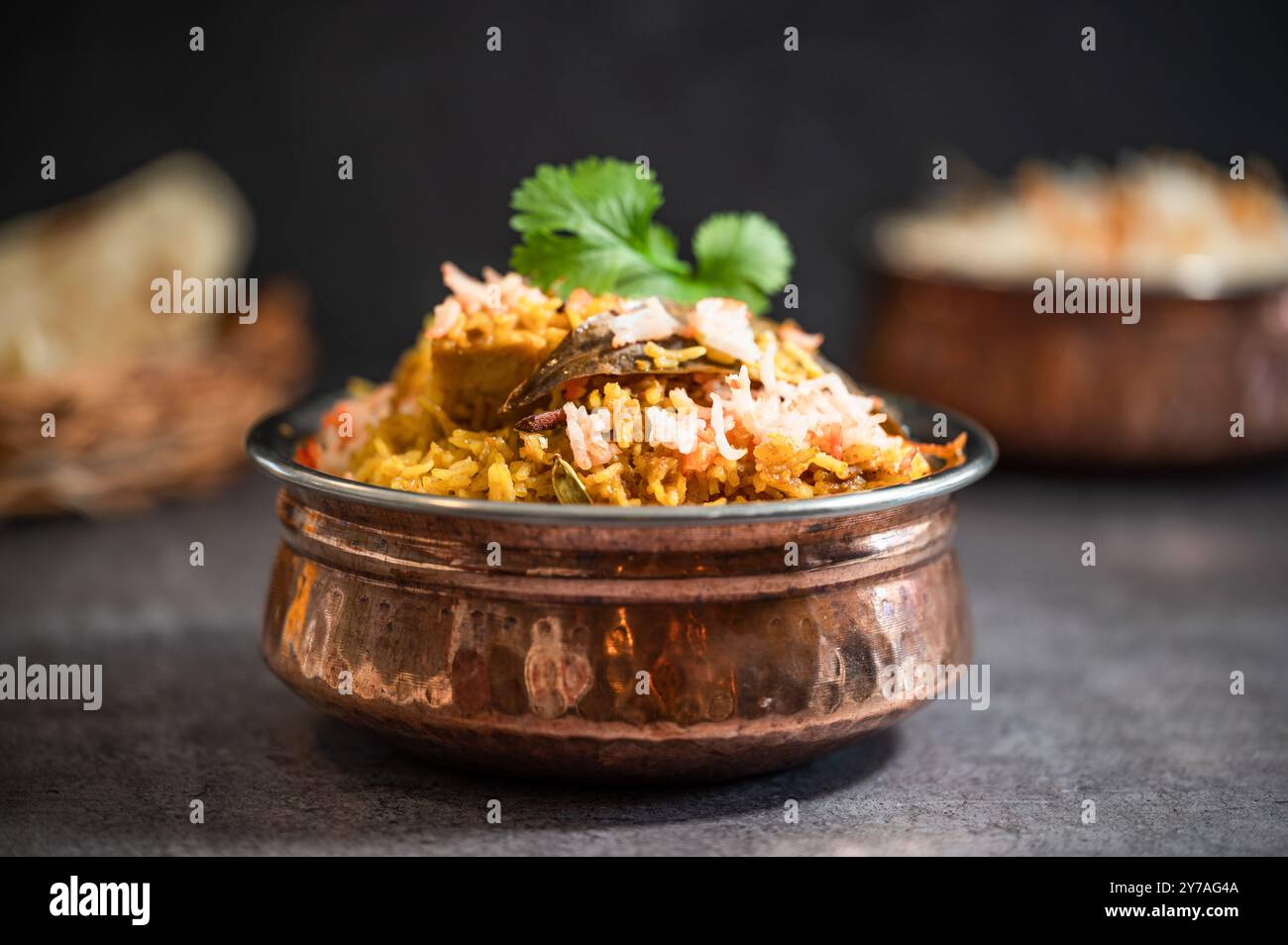 Würziger indischer Biryani-Pulao in goldener Schüssel mit indischem Basmati-Reisgericht mit Hühnerfleisch-Curry Ramadan Kareem, Eid. Servierschale aus Messing mit weißem Rücken Stockfoto