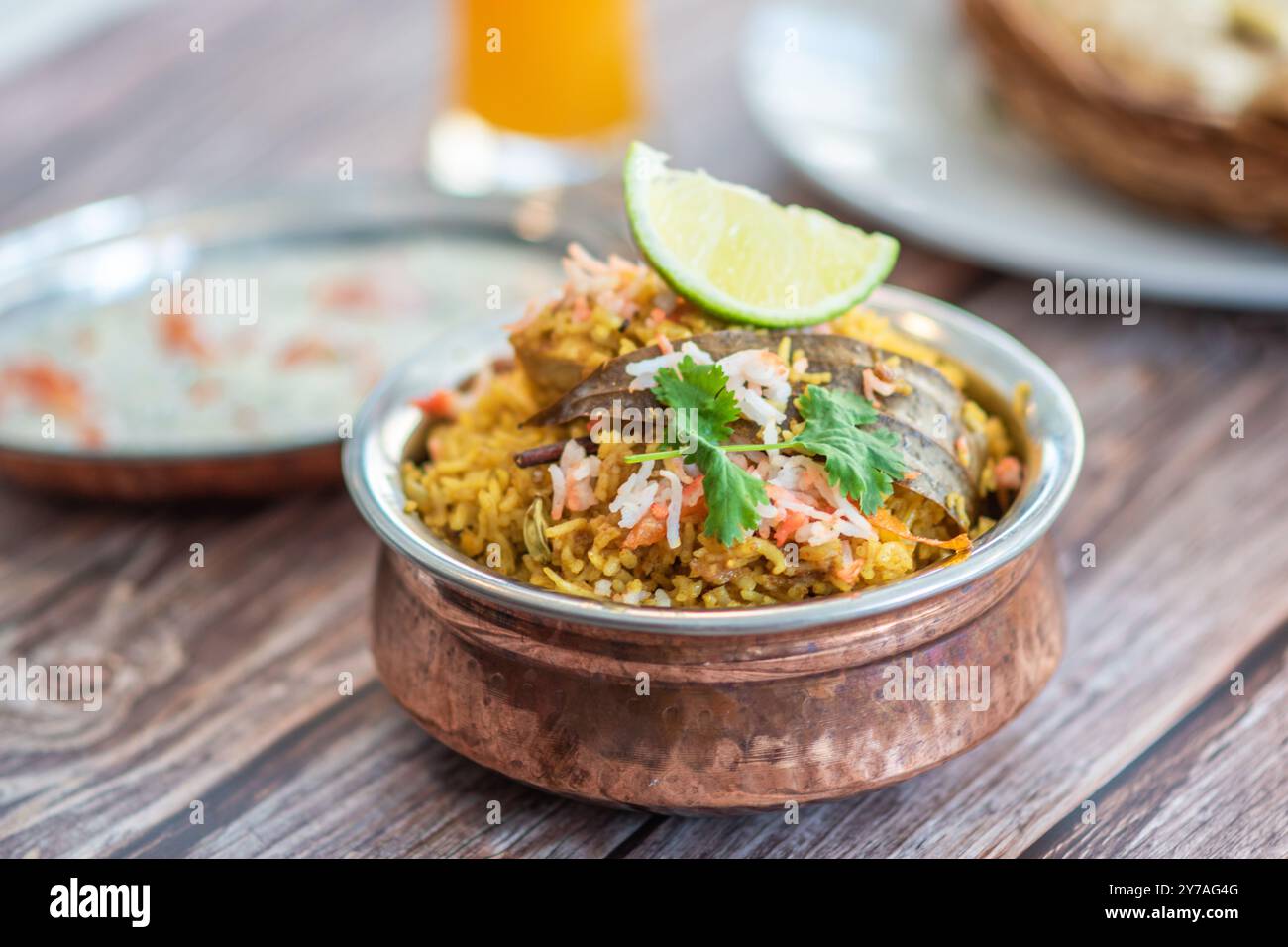 Würziger indischer Biryani-Pulao in goldener Schüssel mit indischem Basmati-Reisgericht mit Hühnerfleisch-Curry Ramadan Kareem, Eid. Servierschale aus Messing mit weißem Rücken Stockfoto