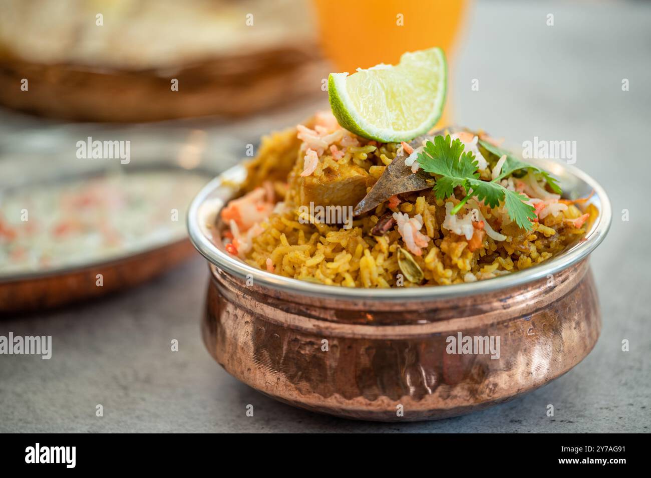Würziger indischer Biryani-Pulao in goldener Schüssel mit indischem Basmati-Reisgericht mit Hühnerfleisch-Curry Ramadan Kareem, Eid. Servierschale aus Messing mit weißem Rücken Stockfoto