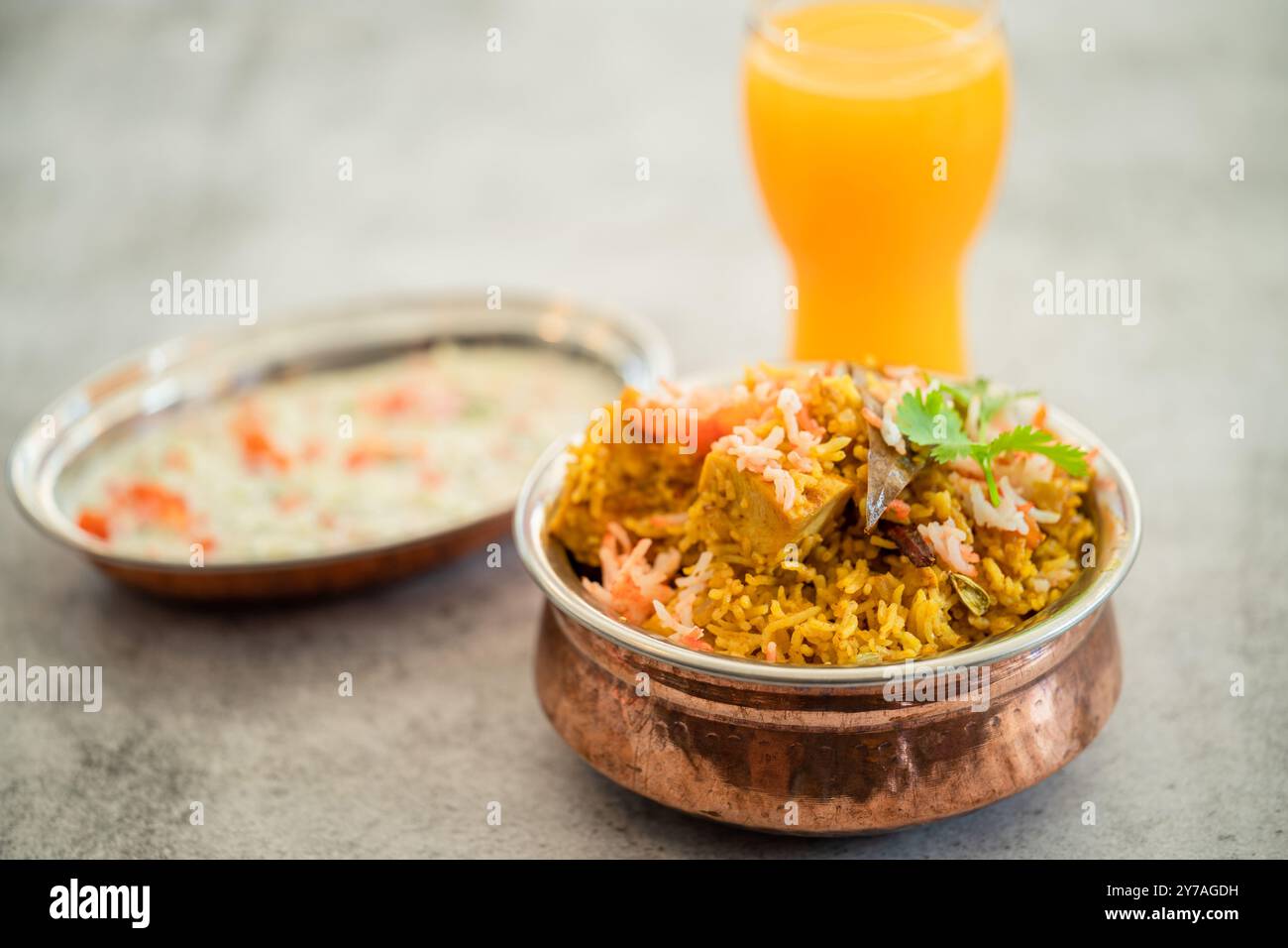 Würziger indischer Biryani-Pulao in goldener Schüssel mit indischem Basmati-Reisgericht mit Hühnerfleisch-Curry Ramadan Kareem, Eid. Servierschale aus Messing mit weißem Rücken Stockfoto