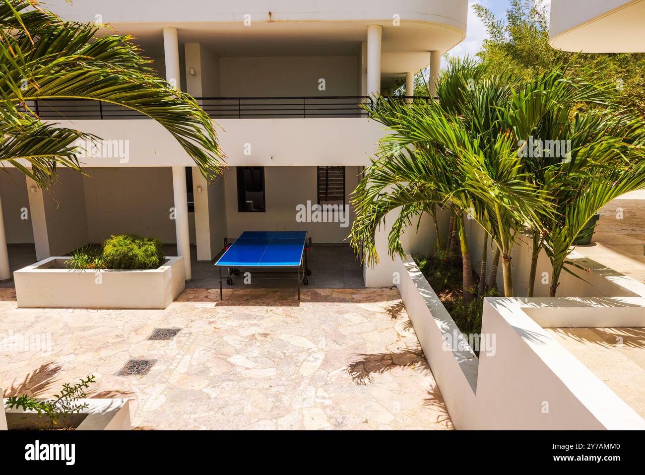 Tischtennis im Freien im Innenhof, umgeben von Palmen und moderner Architektur. Curacao. Stockfoto