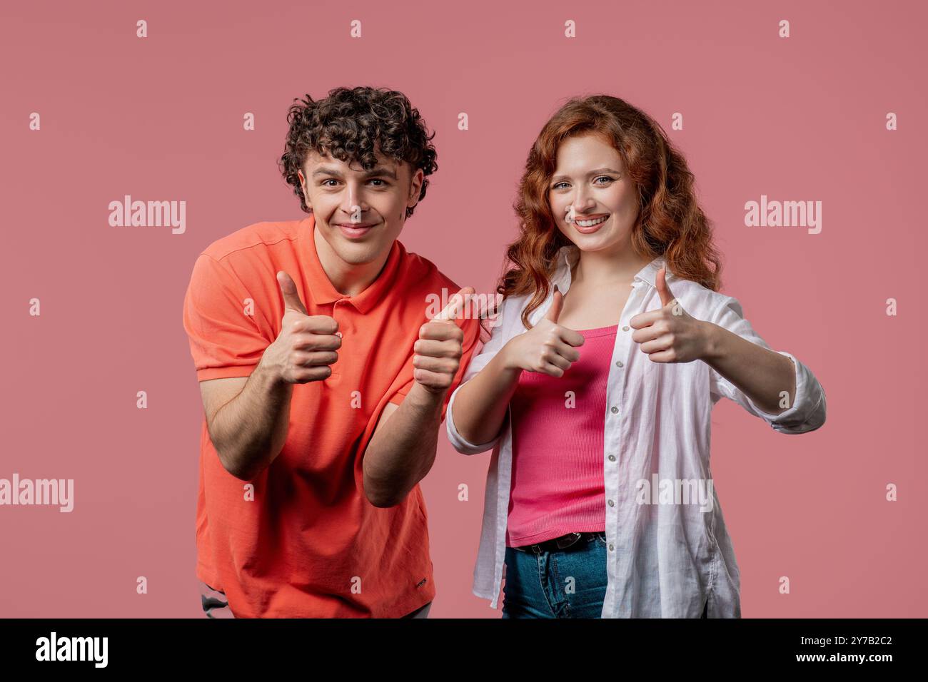 Stilvolle Frau und Mann mit Handzeichen, Daumen hoch Geste. Glückliches Paar, richtige perfekte Wahl, tolles Angebot, rosafarbener Hintergrund. Positive Freunde smil Stockfoto