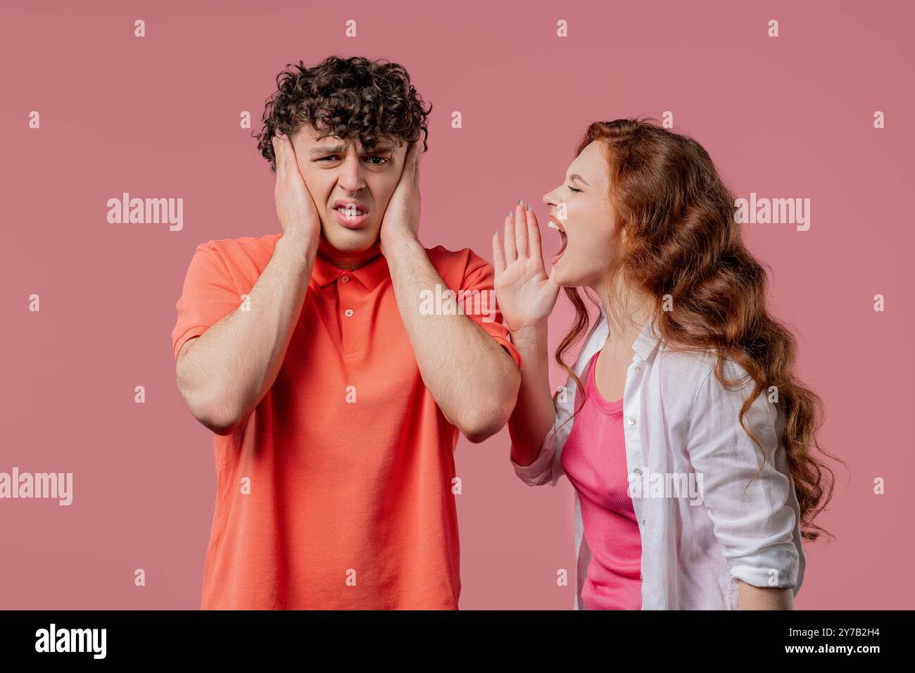 Junge Frau, die Ehemann oder Freund auf rosa anschreit. Müder Mann, der die Augen rollt. Begriff von Konflikt, Streit, Problemen in Paarbeziehungen. Hohe qu Stockfoto