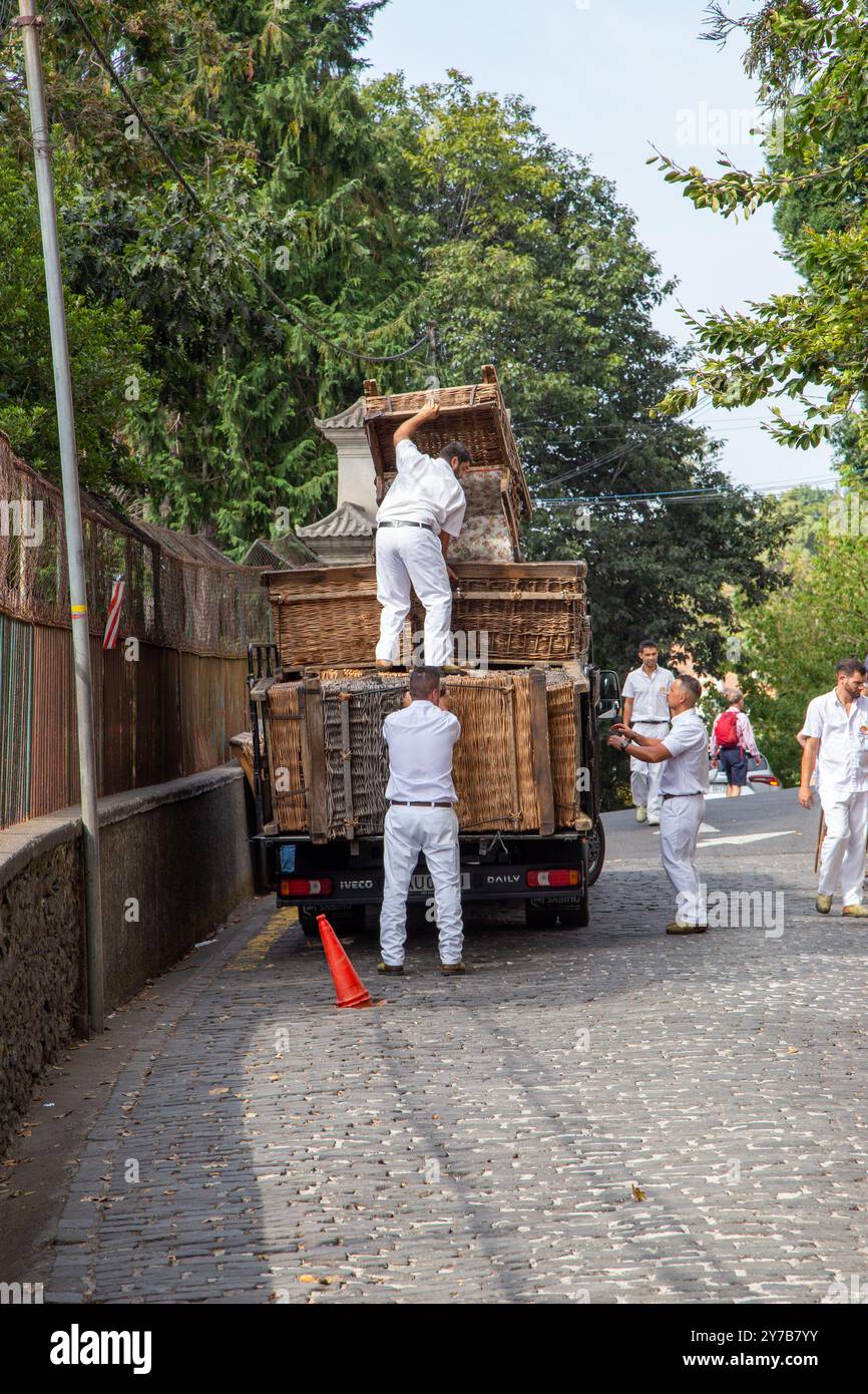 Korbläufer auf der portugiesischen Insel Madeira entladen ihre Körbe von einem Wagen, um sich auf die Rodelfahrten für Touristen vorzubereiten Stockfoto
