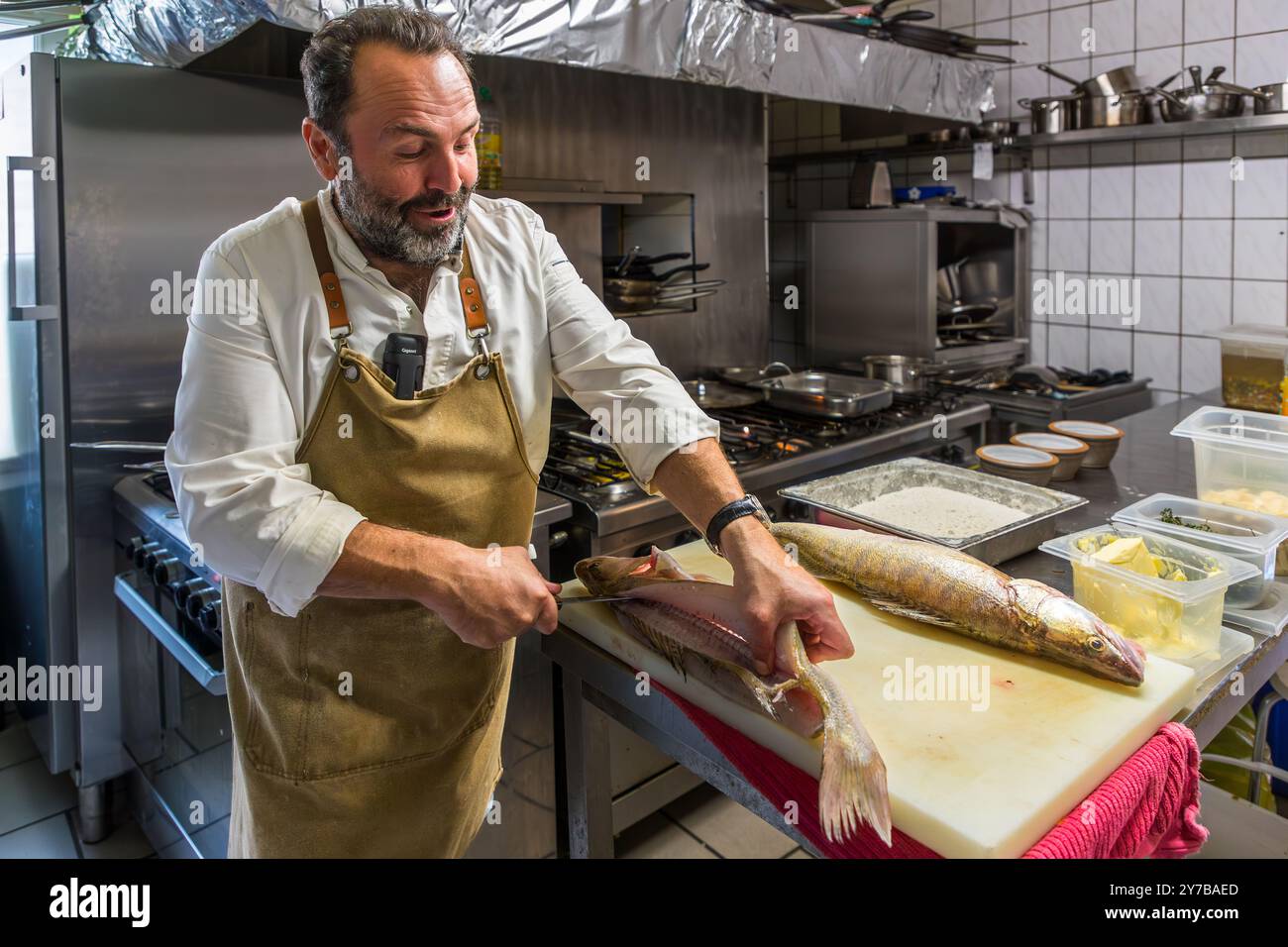 Küchenchef René Bobzin bereitet in der Küche der Bauernstube von Bobzin entbeinten Fisch mit verschiedenen Kartoffelgerichten zu und präsentiert sie persönlich am Tisch der Gäste. Dewichower Straße, Usedom-Süd, Mecklenburg-Vorpommern, Deutschland Stockfoto