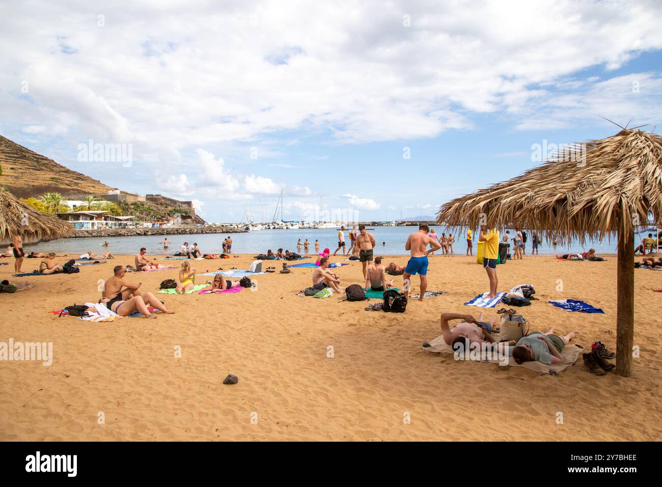 Urlauber, die sich am künstlichen Strand aus importiertem Sand aus Afrika im zweitgrößten Resort auf Madeira, Machico, sonnen Stockfoto