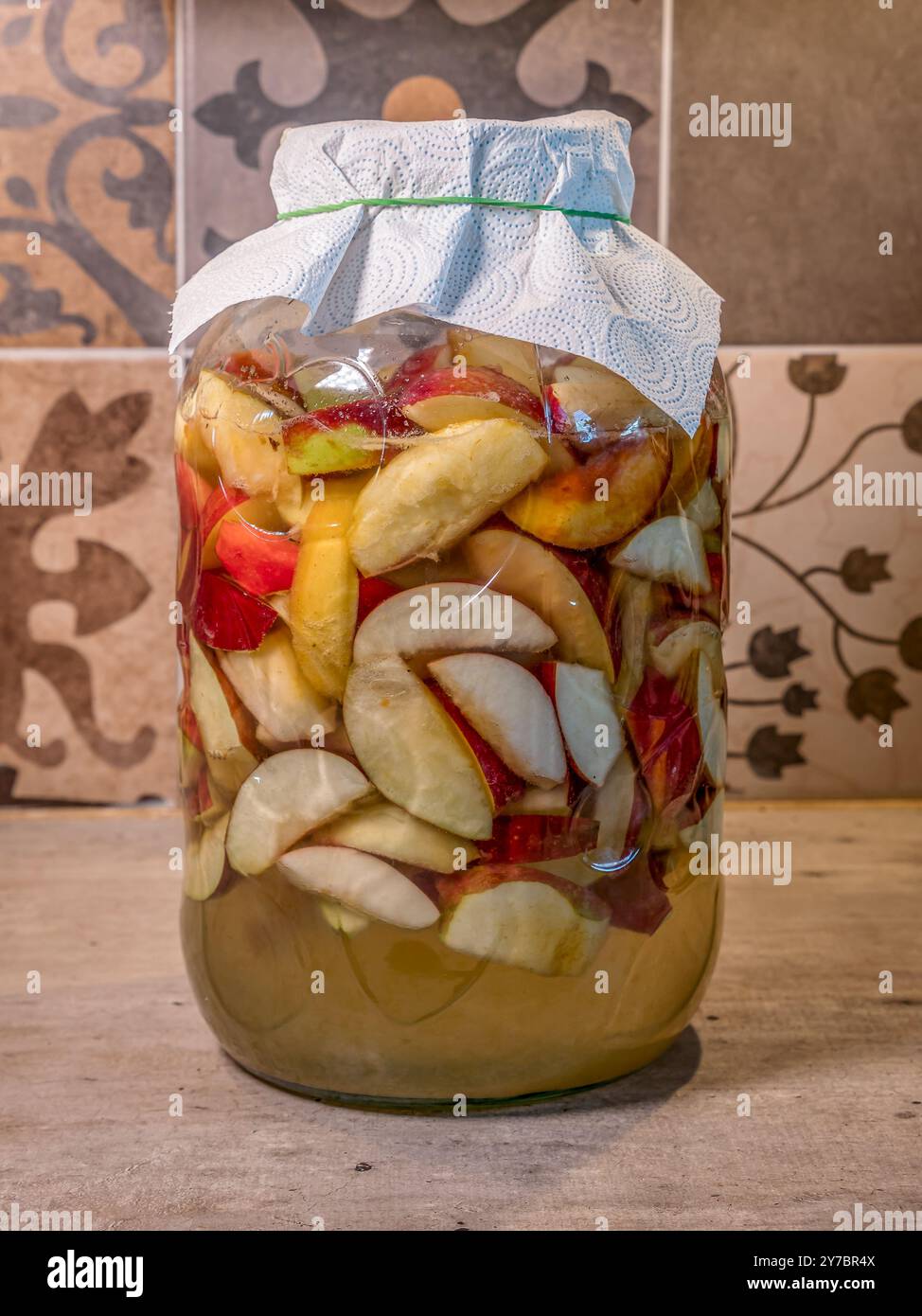 Hausgemachter Apfelessig, der in einem Glasgefäß auf der Küchenplatte zubereitet wird Stockfoto