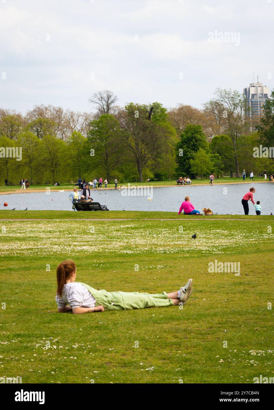 London, England, April 30 2023: Frau liegt im Gras in Kensington Gardens an einem schönen Tag Stockfoto