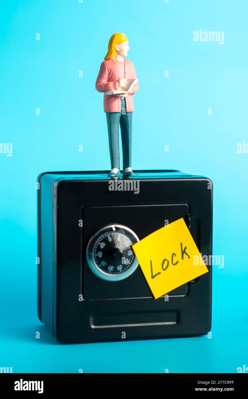 Miniaturfigur auf Safe mit Kombinationsschloss und gelbem Hinweis. Stockfoto