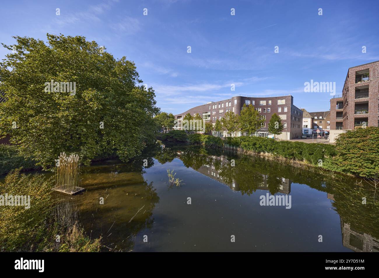 Bäume und moderne Gebäude spiegeln sich auf der Oberfläche des Bocholter AA unter blauem Himmel in Bocholt, Münsterland, Bezirk Borken, Nord-Rh Stockfoto