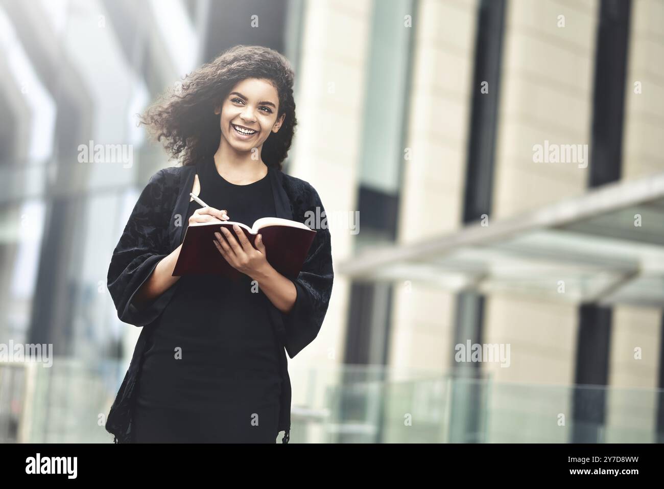 Charmante Afro-amerikanische schöne Happy weiblich, Notizen in Notepad beim Gehen im Freien auf einer Straße der Stadt. Die Bereiche Bildung und Business Konzept mit sp Stockfoto