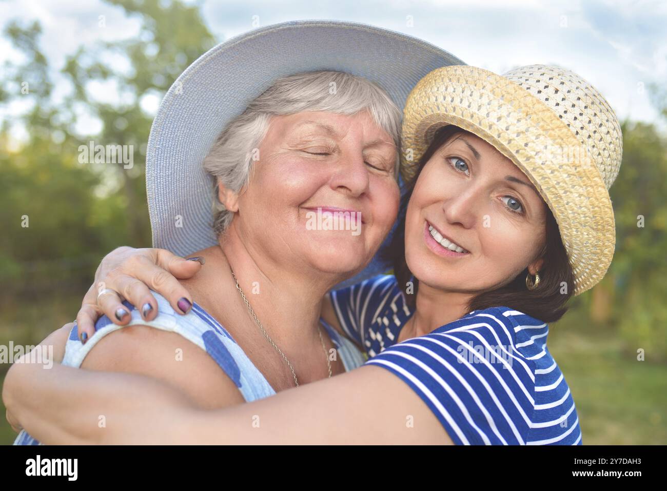 Glückliche Tochter, die ihre lächelnde Mutter umschließt Stockfoto