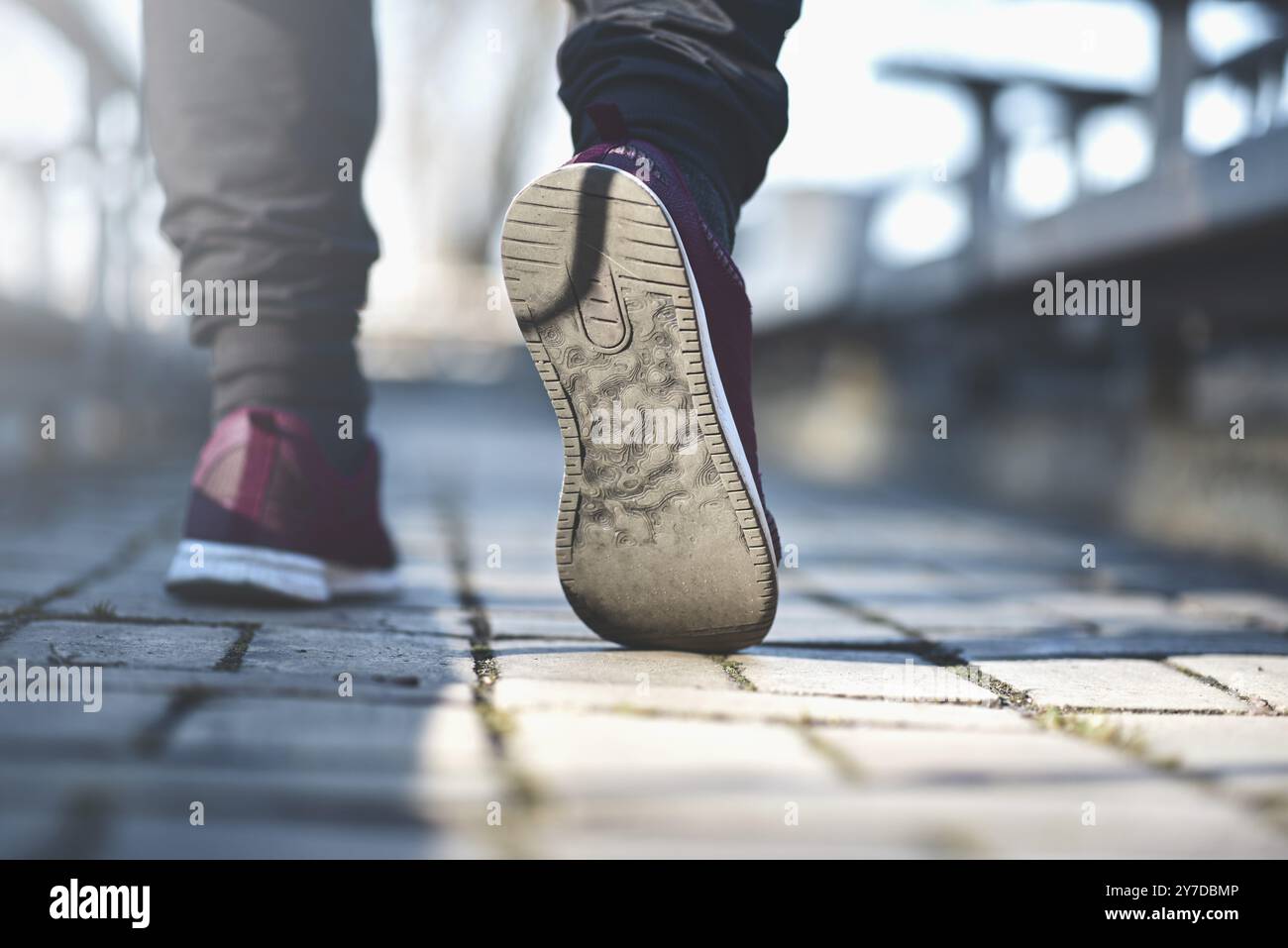 Mann in Turnschuhen geht an einem sonnigen Tag die Straße entlang Stockfoto