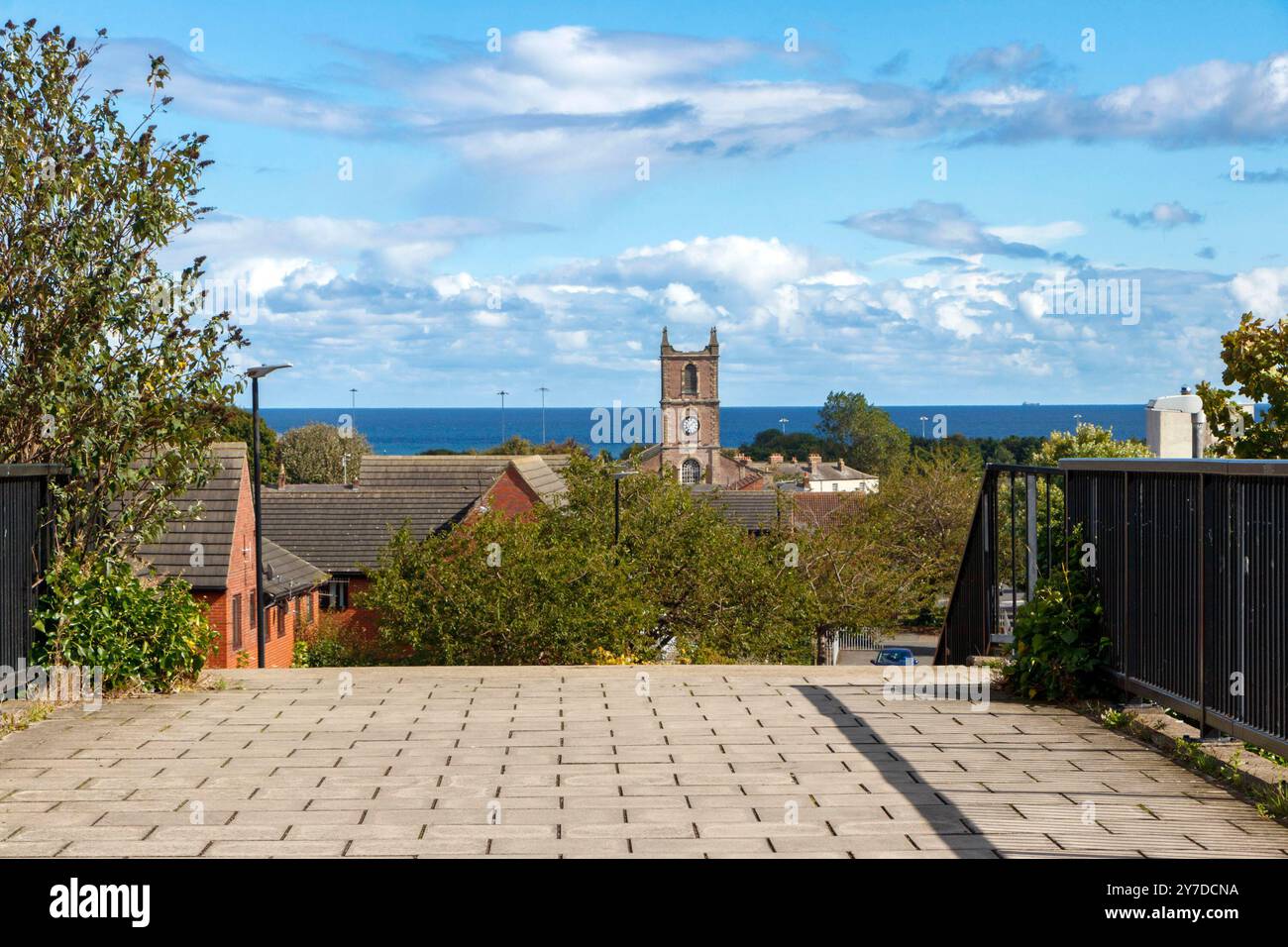 Malerischer Blick auf die Küstenstadt sunderland mit einem markanten Kirchturm, einer Fußgängerbrücke über die Straße und dem blauen Meer Stockfoto