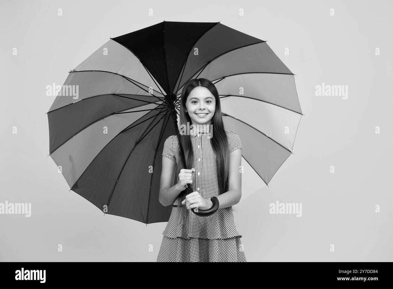 Happy teen Mädchen hält Regenbogen-umbella isoliert auf gelbem Hintergrund, isoliert auf weiß. Fröhlicher Teenager Kind halten Sonnenschirm. Sommerkleid. Stockfoto