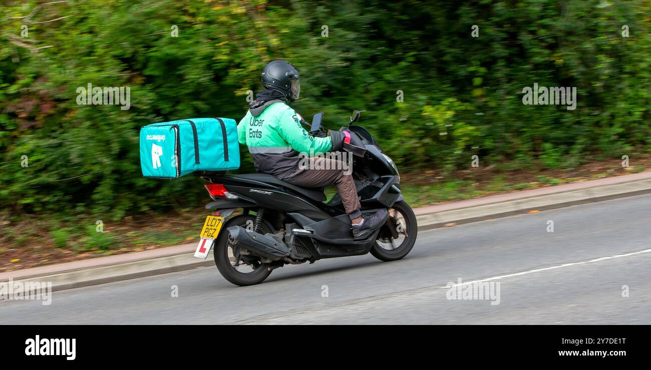 Milton Keynes, Großbritannien - 29. September 2024: Fahrer auf einer Honda WW 125 mit Lebensmitteltasche auf einer britischen Straße Stockfoto