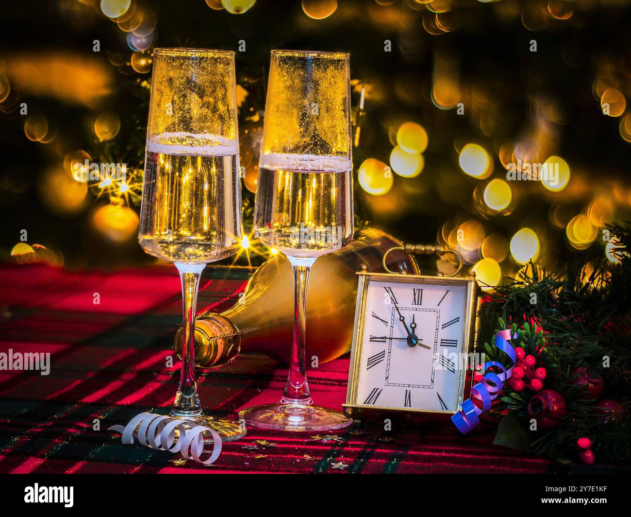 Zwei toastende Sektgläser und Countdown-Uhr auf glitzerndem Hintergrund, frohe Neujahrsfeier Stockfoto