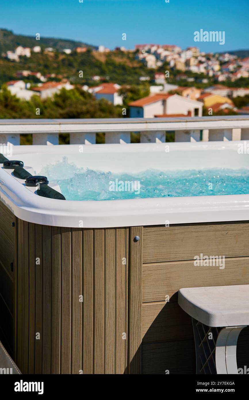 Whirlpool im Freien auf der sonnigen Dachterrasse mit sprudelndem Wasser und komfortablen Sitzgelegenheiten mit wunderschönem Blick auf die touristische Stadtlandschaft. Ort zum Entspannen und Stockfoto