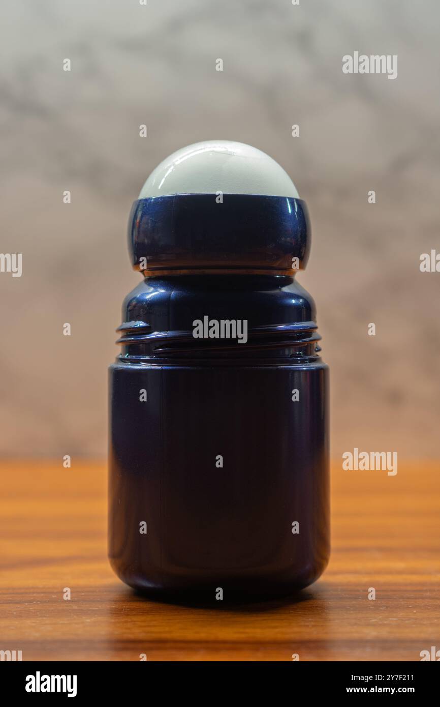 Blaue Anti-Transpirant-Flasche zum Aufrollen auf Holzoberfläche, vor hellem Hintergrund. Schlankes und funktionales Design. Stockfoto