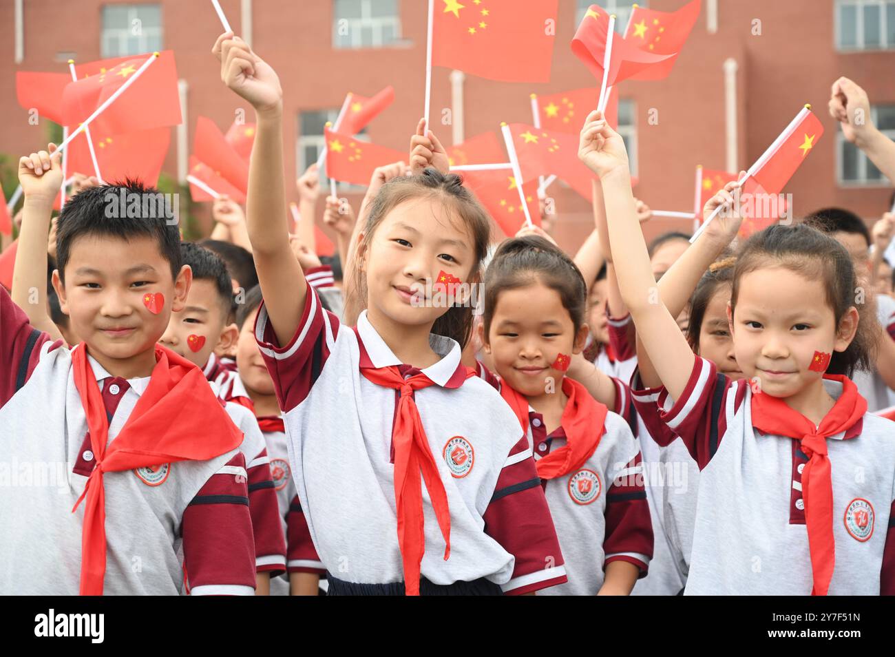 Die Studenten schwenken Nationalflaggen, um den Nationalfeiertag in Xuzhou, Provinz Jiangsu, China, am 30. September 2024 zu feiern. Stockfoto
