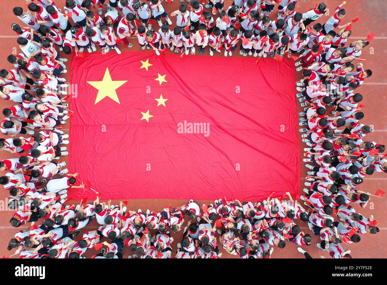 Studenten posieren mit Nationalflaggen, um den Nationalfeiertag in Xuzhou, Provinz Jiangsu, China, am 30. September 2024 zu feiern. Stockfoto
