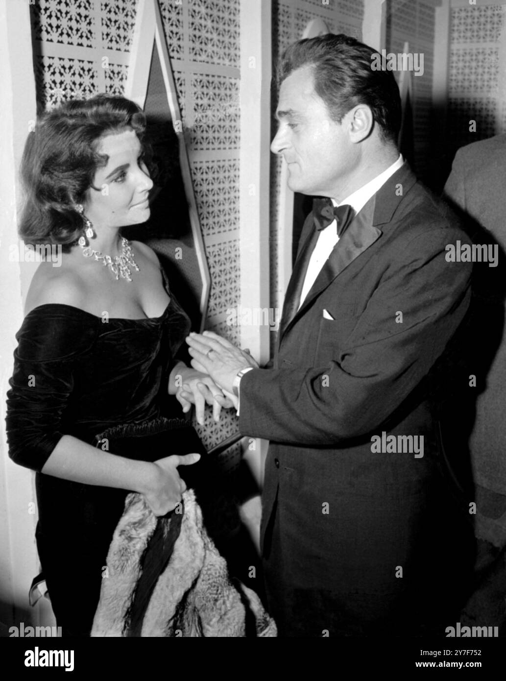 Der Impressario Mike Todd tauscht ein paar coole Worte mit seiner glamourösen Frau, der Schauspielerin Elizabeth Taylor, aus, als sie eine Weile die Hände schnappen, als sie den Kostümball in Hollywood besuchten. 30. Oktober 1957. Stockfoto