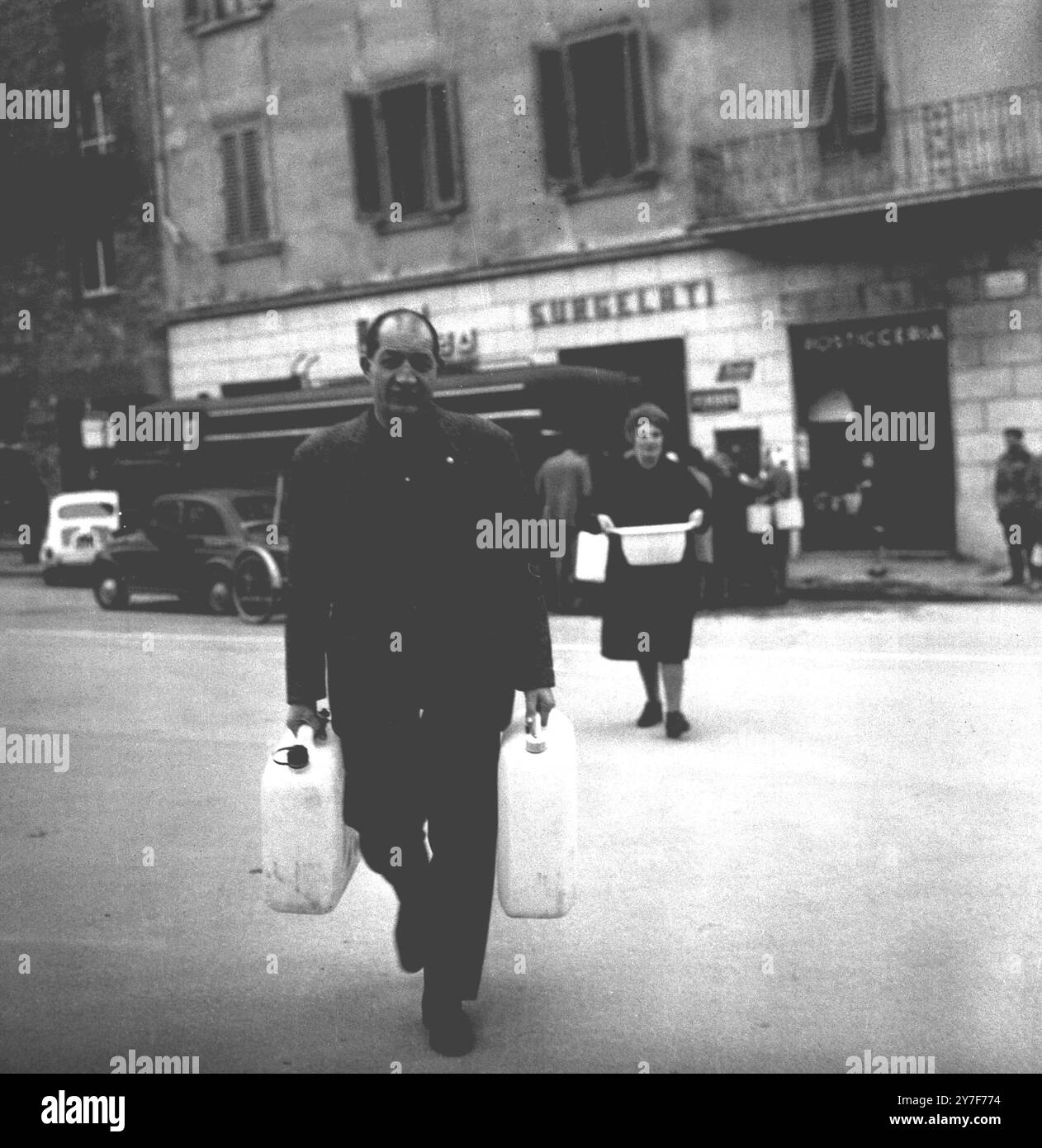 Der ehemalige Radsport-Weltmeister Gino Bartali nimmt wie Tausende anderer Einwohner des verwüsteten Florenz Trinkwasser aus einem Wasserwagen auf und transportiert es in Containern nach Hause. Die Wasserversorgung von Florenz ist wegen des Hochwassers außer betrieb. November 1966. Stockfoto