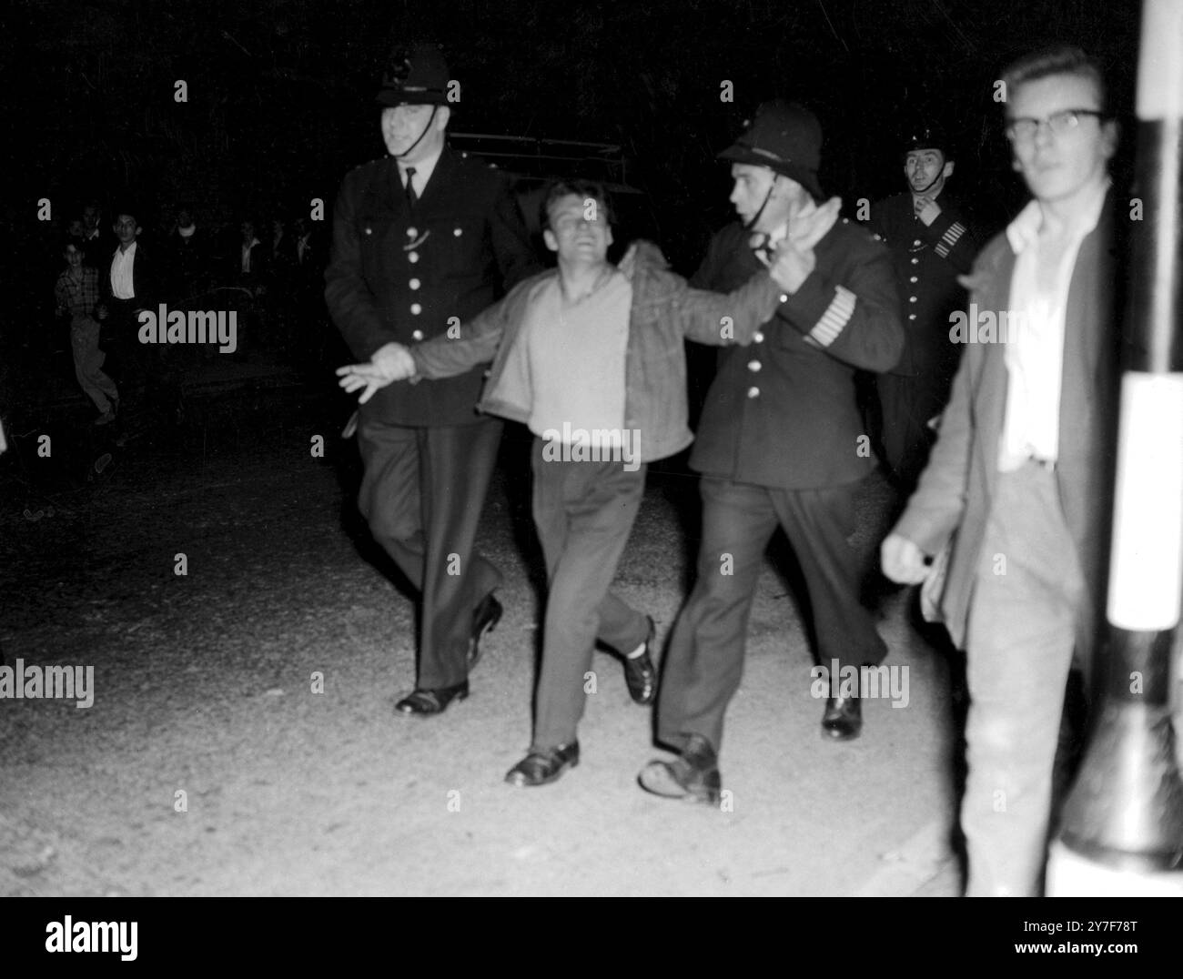 IN NOTTING HILL BRECHEN ERNEUT RACE UNRUHEN AUS. Zwei Polizisten führen einen Demonstranten weg, der gestern Abend in Notting Hill an Rassenunruhen beteiligt war. Am Abend wurden mehr als 100 Polizisten in der Gegend versammelt, einige mit Polizeihunden; aber Hooligans stürmten die Oxford Gardens herunter und zerschlugen Fenster in den farbigen Häusern, bevor die Polizei einziehen konnte. Das war die dritte Nacht mit Rassenproblemen im Bezirk. 2. September 1958 Stockfoto
