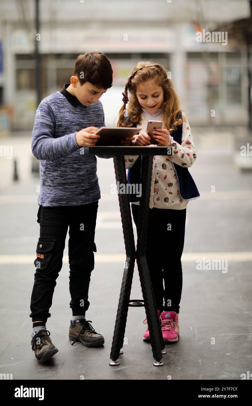 Kinder spielen mit ihrem Smartphone und ipad in ihrem Haus ohne elterliche Aufsicht in der türkischen Stadt Gaziantep. Die Tatsache, dass viele Kinder in jungen Jahren mit Mobiltelefonen und Tablets spielen, hat Probleme in Bezug auf ihre kognitive Entwicklung und ihre Sicherheit vor möglichen Strahlungen und aus dem Internet aufgeworfen. Die weit verbreitete Nutzung von Technologie hat die jüngsten Mitglieder der meisten Gesellschaften getroffen. Smartphones und Tablets haben oft traditionelle Kinderaktivitäten wie Puppen, Brettspiele und Spiele im Freien ersetzt. Kinder werden oft an den Geräten festgeklebt Stockfoto