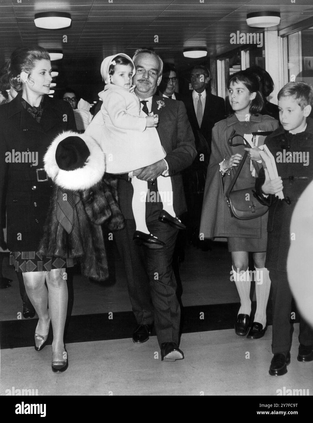 Prinz Rainier III. Von Monaco trägt seine dreijährige Tochter Prinzessin Stephanie, als er und die in Amerika geborene Prinzessin Grace von Madrid aus in London flogen. Rechts sind die beiden älteren Kinder, Prinz Albert, 10, und Prinzessin Caroline, 11. 31. Oktober 1968 Stockfoto