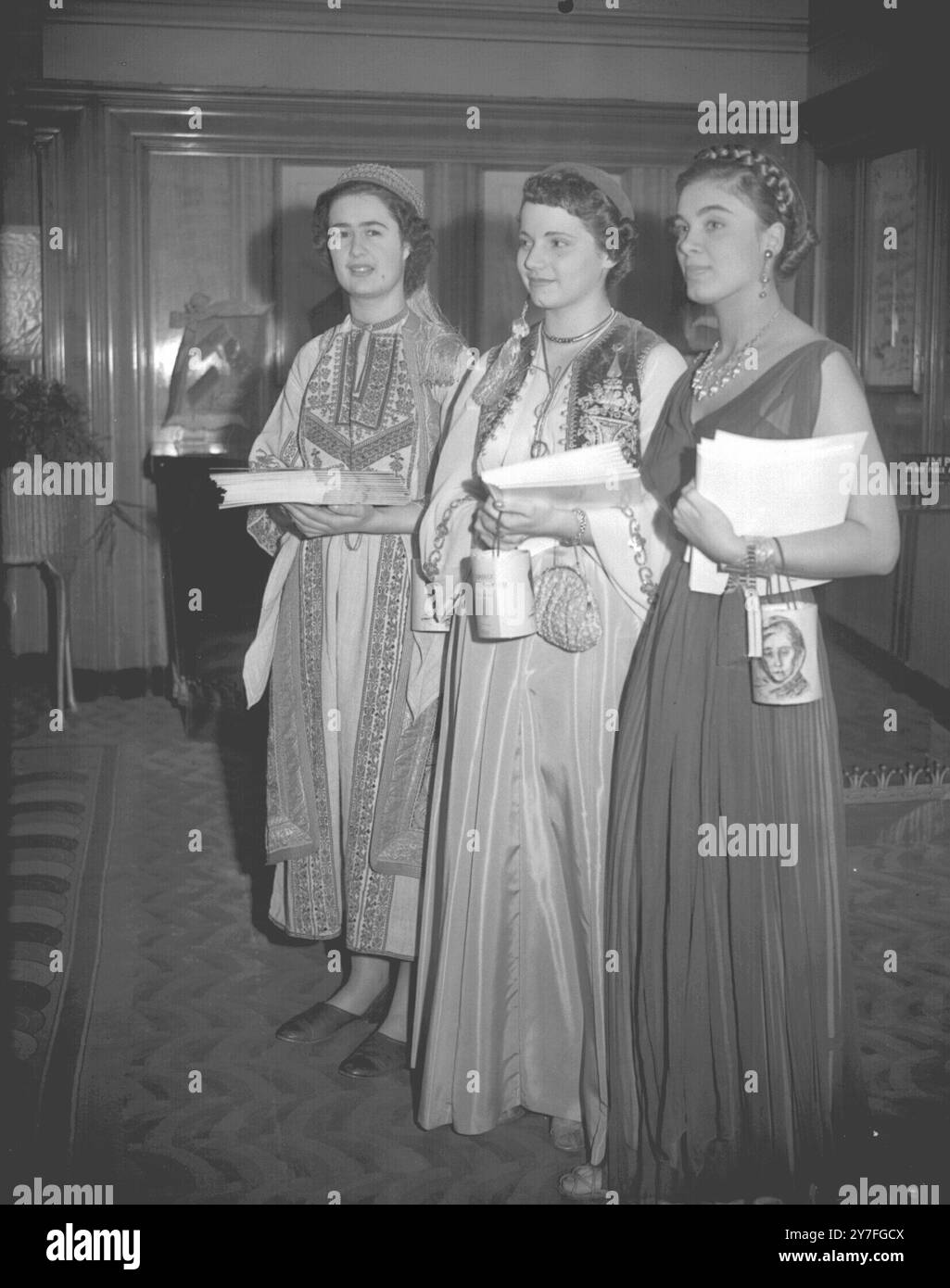 Diese drei griechischen Mädchen, die jetzt in London leben, trugen ihre Nationalkleidung und fungierten als Programmverkäufer bei der Weltpremiere des Films „das Haus auf dem Platz“, dessen Erlöse dem Beratungskomitee Help t Greece zugute kamen. Von links nach rechts sind Fanny Argenti, Mary Goulandris und Alexia Stephanides. Dezember 1951 Stockfoto