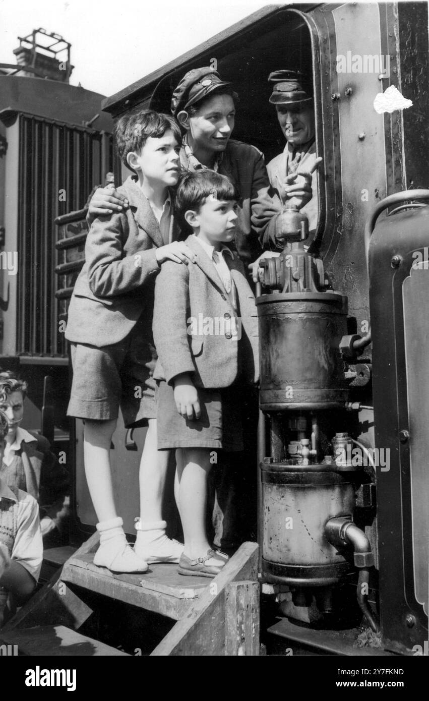 Es ist ein großer Nervenkitzel für Stephen, 12, und seinen Bruder Peter Cockburn, 6, vom College Place, Brighton, die von Feuerwehrmann F. Floate und Fahrer W. Penfold (R) über Brightons alten Zug gezeigt werden. August 1952 Stockfoto Es ist ein großer Nervenkitzel für Stephen, 12, und seinen Bruder Peter Cockburn, 6, vom College Place, Brighton, die von Feuerwehrmann F. Floate und Fahrer W. Penfold (R) über Brightons alten Zug gezeigt werden. August 1952 Stockfoto